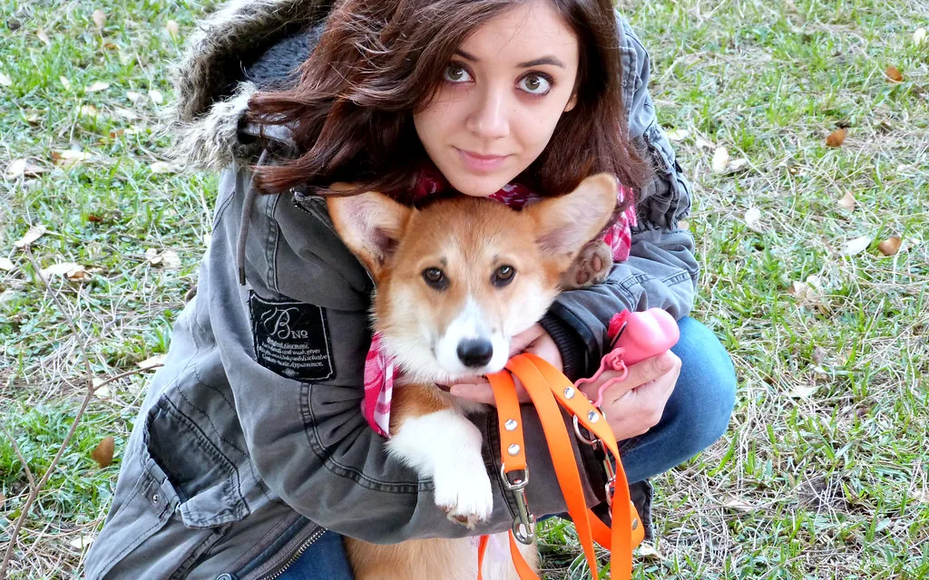 A young woman hugging a dog on a lead